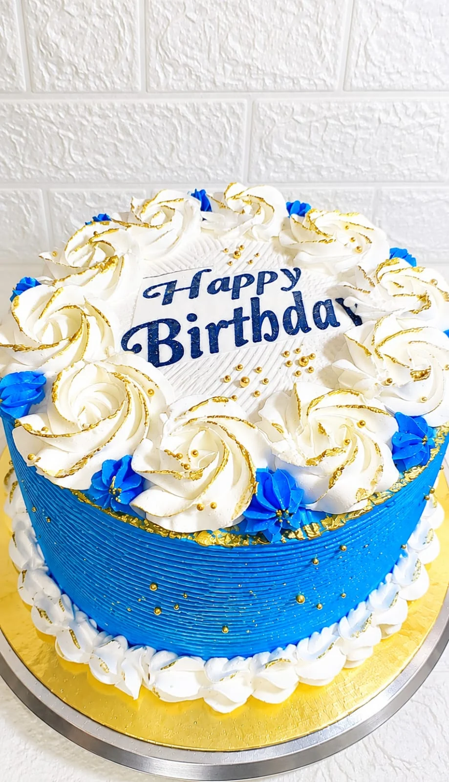 Queque azul con flores de decoración color crema y letrero de cumpleaños