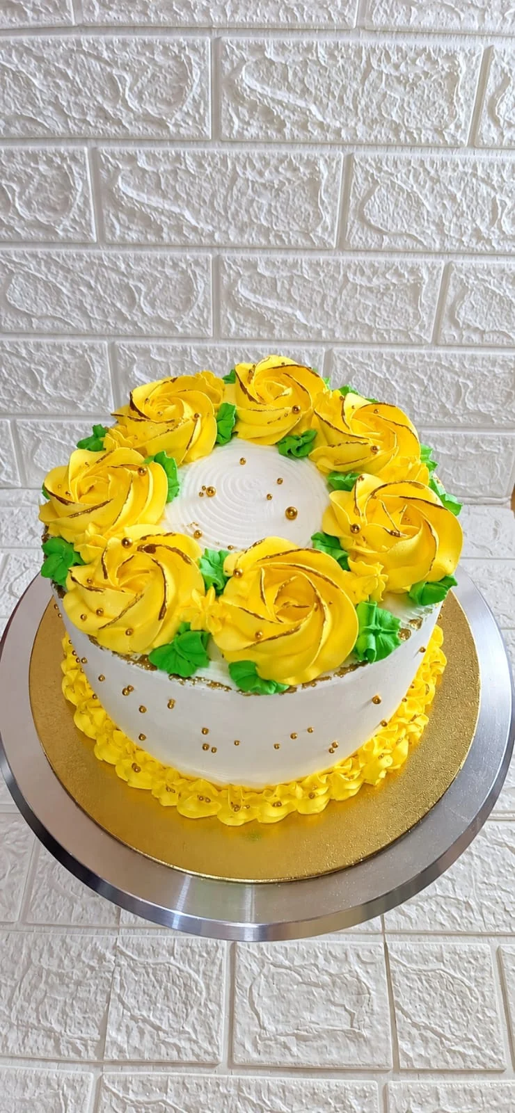 Queque amarillo y blanco con flores amarillas y hojas verdes