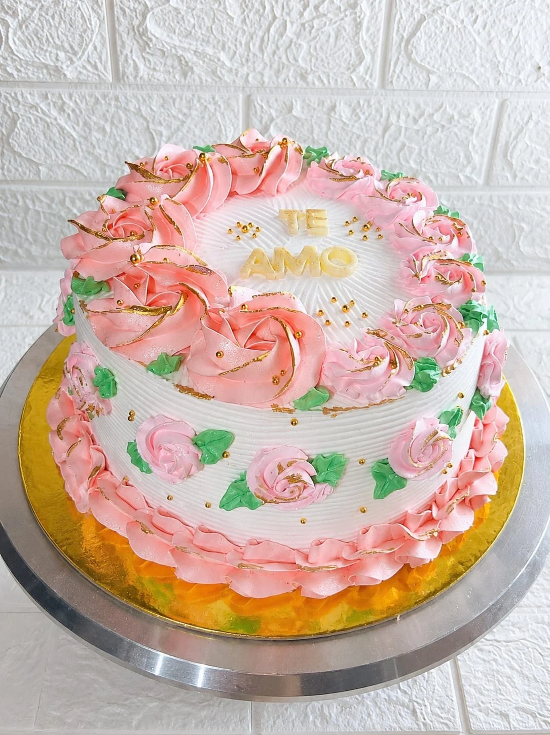 Queque blanco con rosas rosadas y hojas verdes decoradas a mano