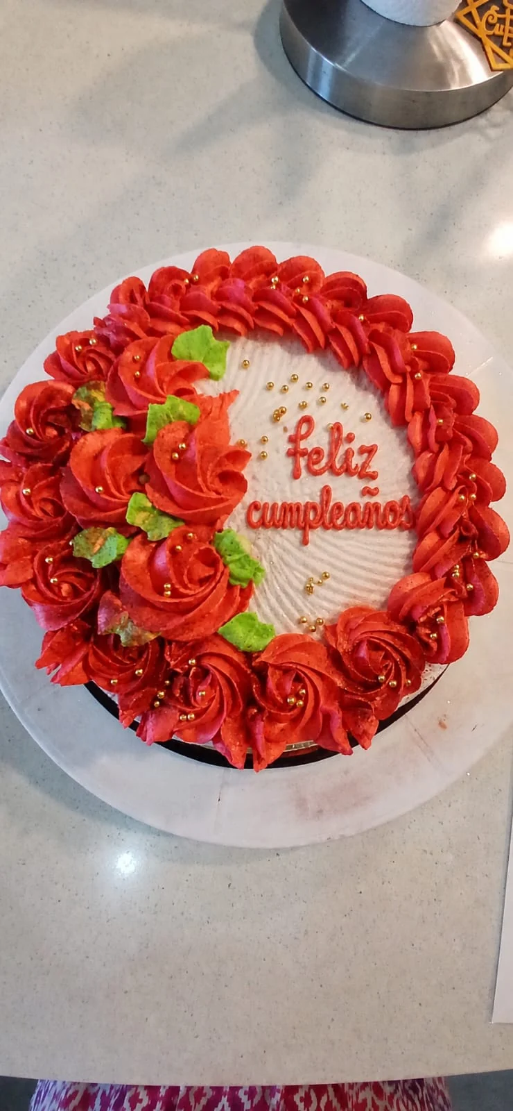 Queque redondo decorado a mano por Dianet con rosas rojas y hojas verdes
